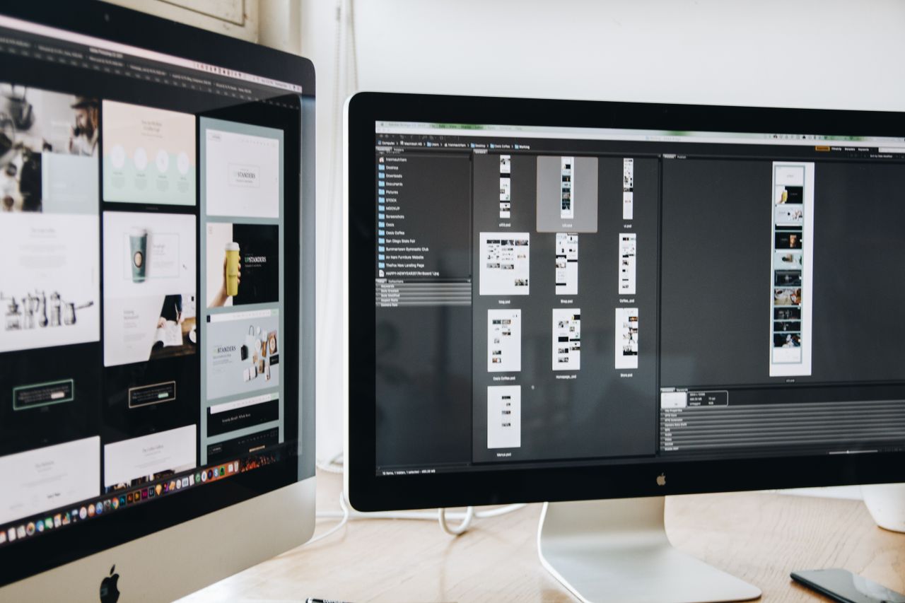 Un espace de travail moderne avec deux écrans d’ordinateur affichant des projets de design web, mettant en avant la technologie et la productivité.